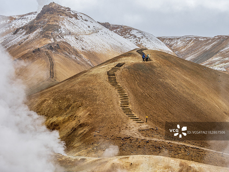 蒸汽腾腾的温泉和五彩斑斓的火山岩山脉，徒步小径，赫维达利尔地热区，凯尔林加菲尔，冰岛高地，冰岛，欧洲图片素材
