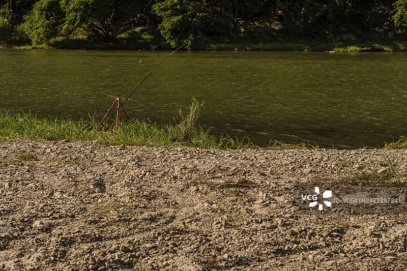 钓鱼竿靠在金属支架上，钓线投向韩国的一条河流。图片素材