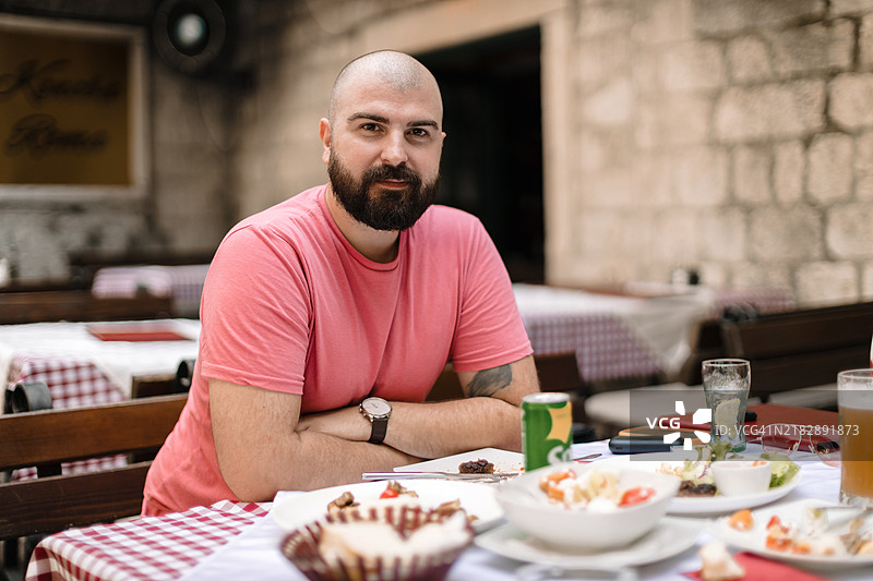 年轻男子坐在科托尔历史悠久的老城餐厅里图片素材