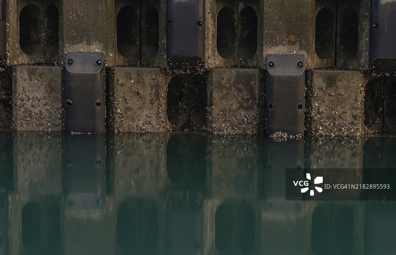 混凝土块和钢墙在绿色水中的倒影图片素材