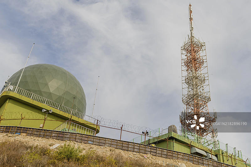 一座带有绿色圆顶和通信塔的雷达站，背景是部分多云的天空，位于韩国图片素材