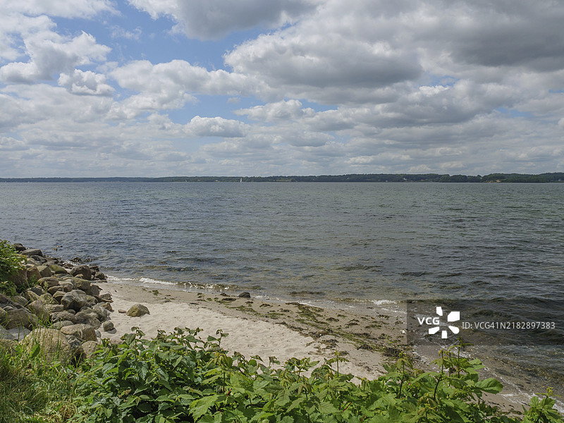 石头沙滩，俯瞰平静的海面，天空部分多云，位于德国施莱斯维希-霍尔斯坦州的格吕克斯堡图片素材