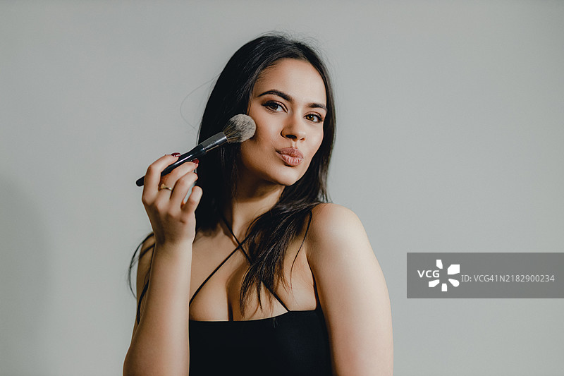 年轻女性在涂腮红化妆图片素材