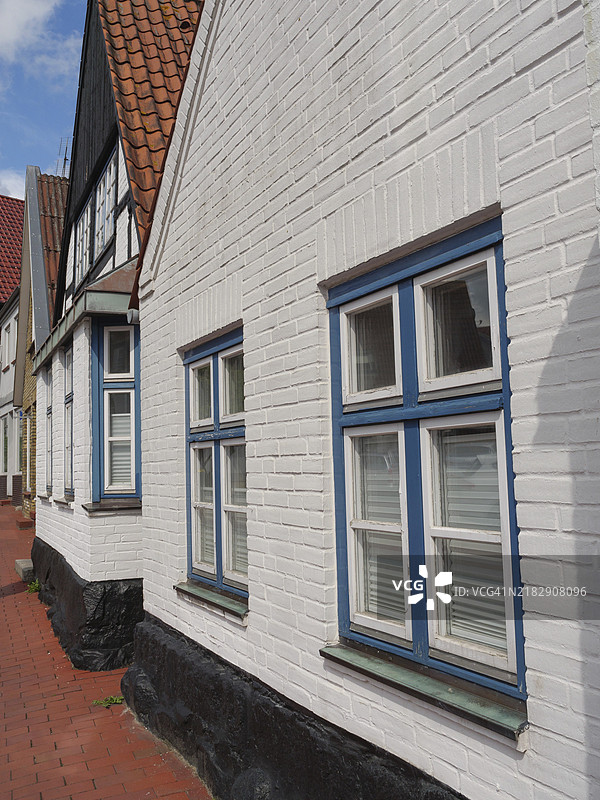德国欧洲施莱斯维希-霍尔斯坦州卡彭村白色房屋的特写，蓝色窗框和瓦屋顶。图片素材