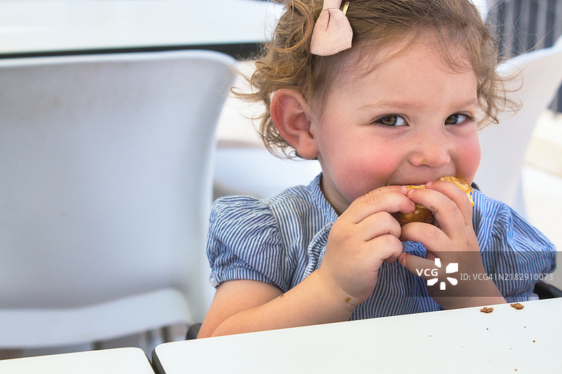 调皮的小女孩吃着食物，微笑着看向镜头，美国，USA图片素材
