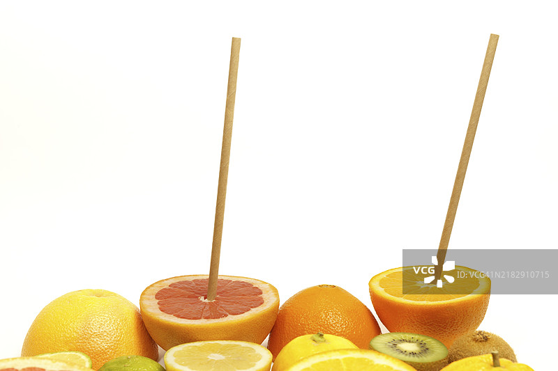 新鲜水果切成两半，旁边放着一根吸管，背景为白色。橙子、葡萄柚、柠檬、猕猴桃。图片素材