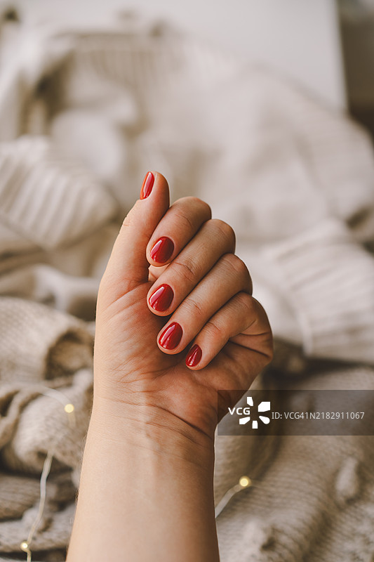 温馨的冬季环境中，一只手展示着红色指甲油图片素材