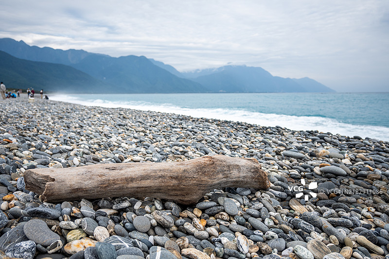 花莲七星潭海滩的岩石海滩上的漂流木与山脉图片素材