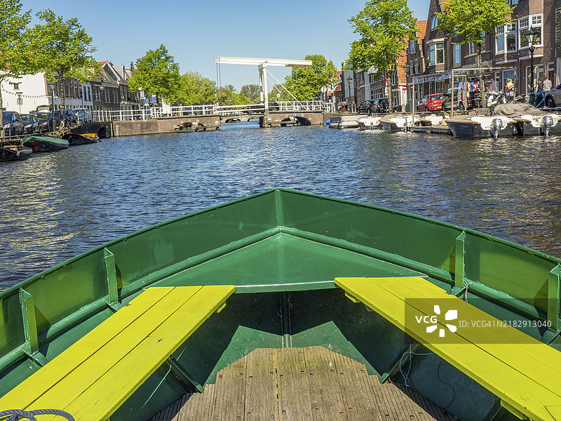 从船上俯瞰运河，周围是房屋和树木，一座白色桥梁横跨运河，阿尔克马尔，荷兰图片素材