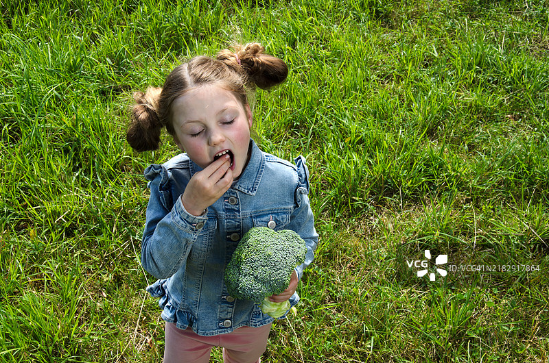 一个小女孩在品尝生西兰花图片素材