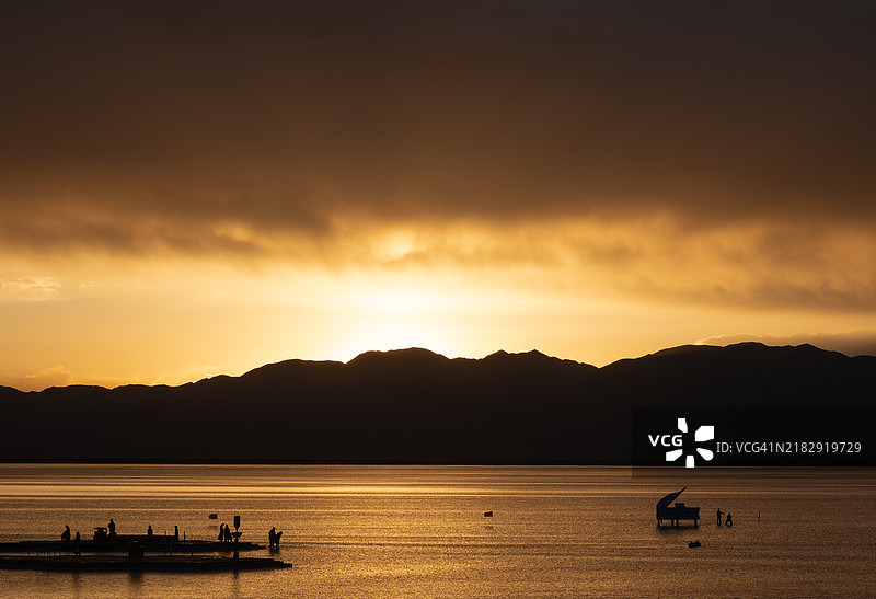 夕阳下，湖面上船上人们的剪影与天空相映成趣， 中国图片素材