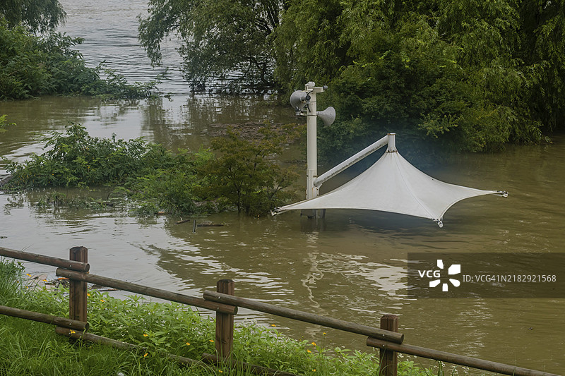白色遮阳篷覆盖在被洪水淹没的河流上，野餐桌被大雨淹没在水中，地点位于韩国大田。图片素材