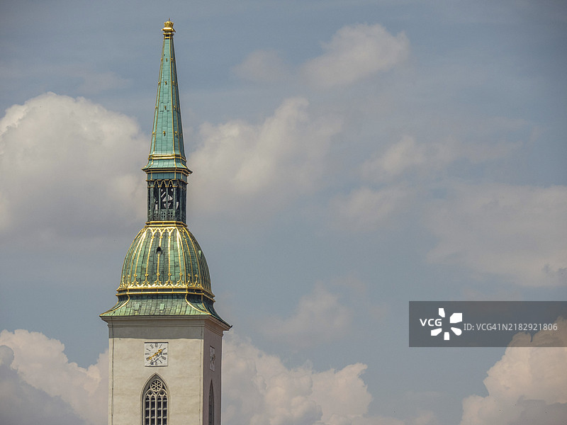 布拉迪斯拉发，斯洛伐克，蓝天白云下的教堂塔楼，金色尖顶和绿色屋顶。图片素材