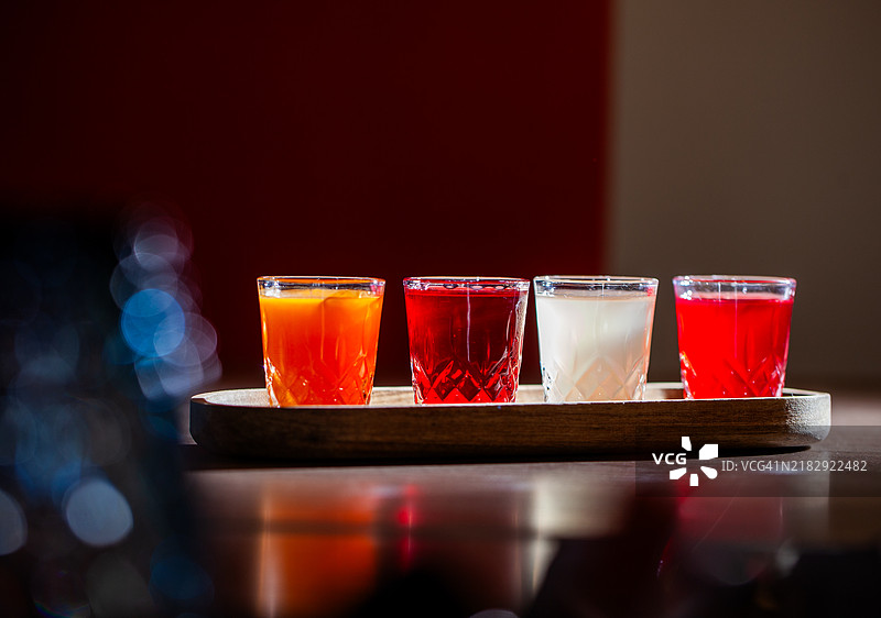 四杯色彩缤纷的酒精饮料放在木托盘上图片素材