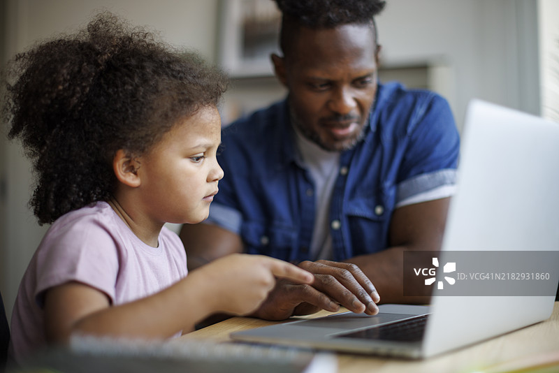 父亲和女儿在家使用笔记本电脑图片素材