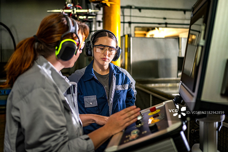 经验丰富的数控操作员指导年轻学员图片素材