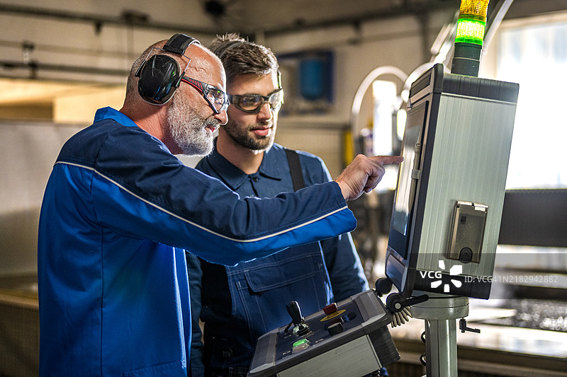 熟练的操作员指导学徒使用水刀切割机图片素材