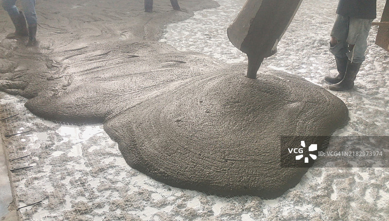 工人们正在帮助将液态混凝土倒在湿混凝土地面上。图片素材