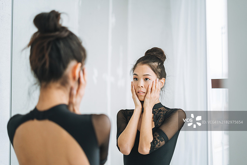 年轻美丽的日本芭蕾舞者穿着芭蕾裙在舞蹈室的镜子前图片素材