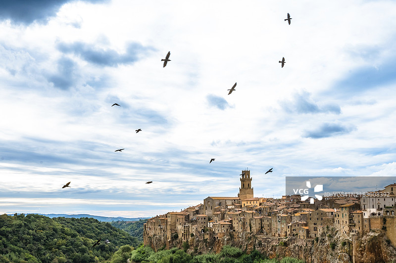 鸟儿在托斯卡纳的索拉诺中世纪小镇上空盘旋图片素材