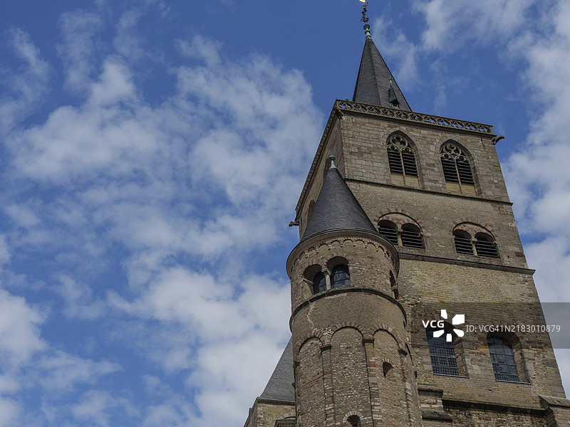 德国特里尔一座罗曼式教堂的尖塔，蓝天和零星云朵。图片素材