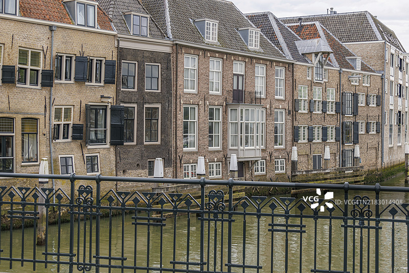 荷兰多德雷赫特老城区运河上的宁静场景，历史建筑有些倾斜，窗户装饰精美。图片素材