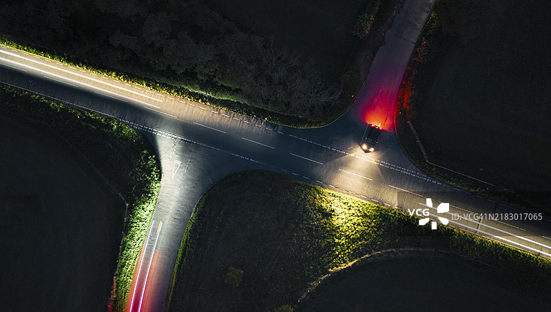 夜间无人机/空中视角下，一辆汽车在路口停靠，路上的交通模糊不清。图片素材