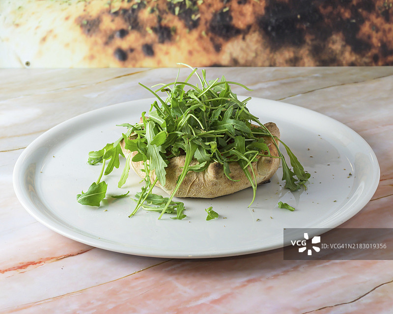 阿根廷风味的富卡萨披萨，内含一层马苏里拉奶酪，配有切片洋葱和更多奶酪，特写放在木桌上的盘子里。水平俯视图，披萨。图片素材