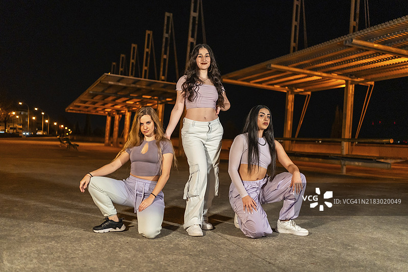 三位年轻女性在夜晚摆姿势，组成城市舞蹈团体的肖像图片素材