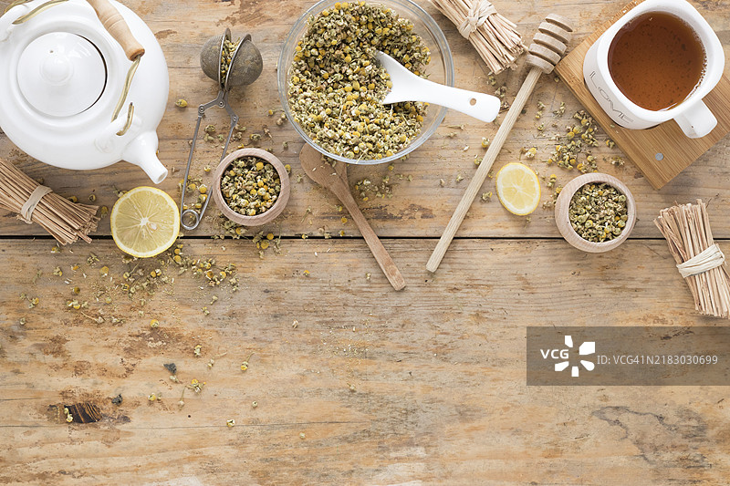 干燥的中国菊花、茶壶、茶漏、蜂蜜勺、容器、新鲜柠檬茶、木桌图片素材