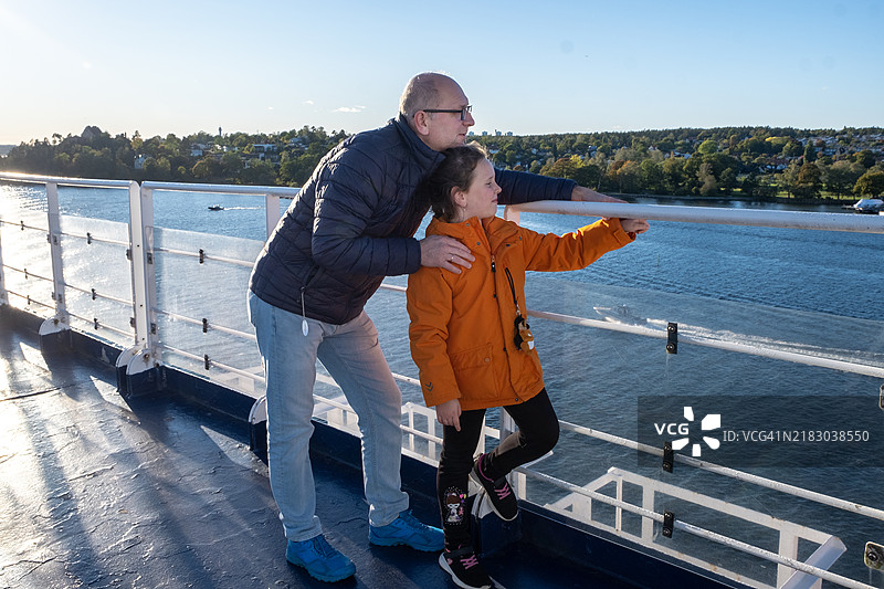 一名50岁的男子和一名9岁的女孩在游轮甲板上欣赏斯堪的纳维亚的北部风景。图片素材
