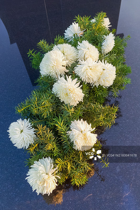 白色菊花静静地躺在墓碑上。图片素材