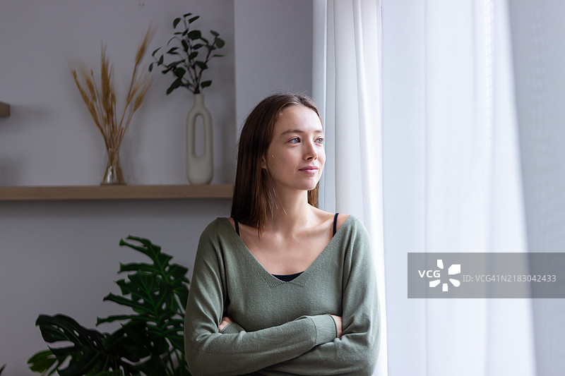 年轻女性望着窗外，满怀希望和积极地思考未来图片素材