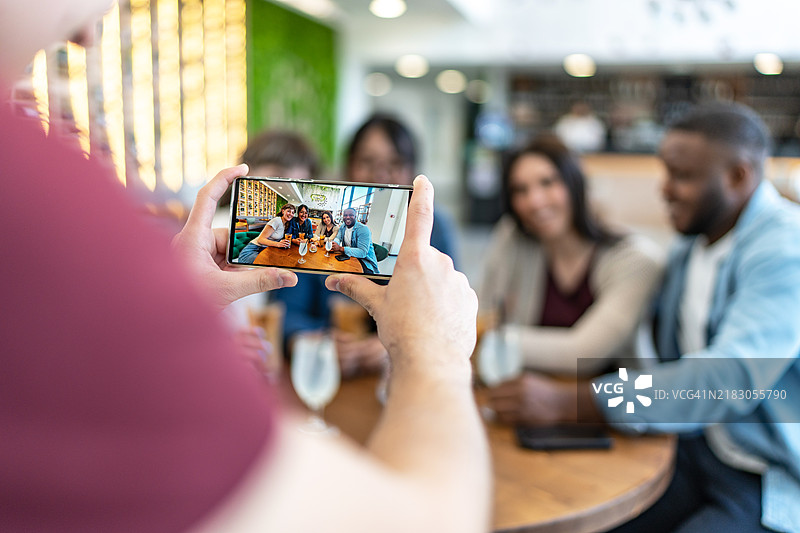 男性朋友在咖啡馆为他的朋友们拍照图片素材