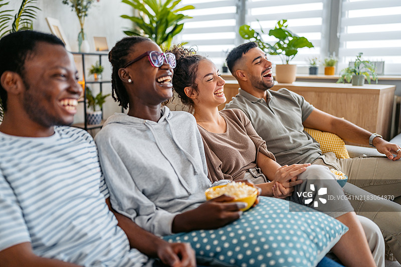 一群朋友在客厅一起看电影时吃爆米花图片素材