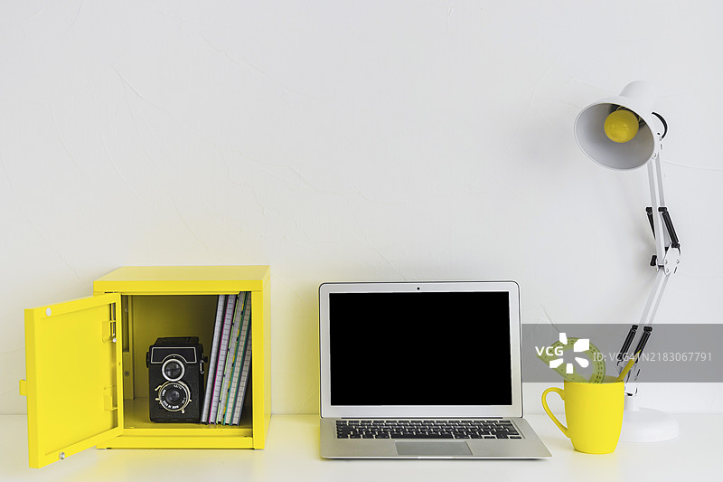 白色时尚工作空间，白色和黄色搭配，配有笔记本电脑和黄色盒子图片素材