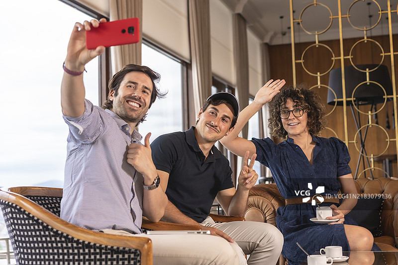 团队合作，坐在酒店的咖啡厅里摆姿势拍自拍。图片素材