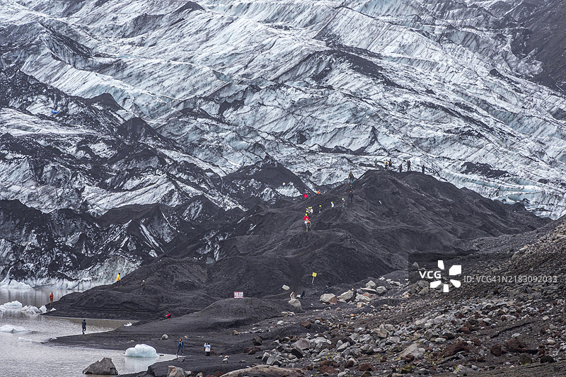 游客团体在冰川湖，冰川徒步旅行，索尔海马冰川，湖上的冰山，冰岛，欧洲图片素材