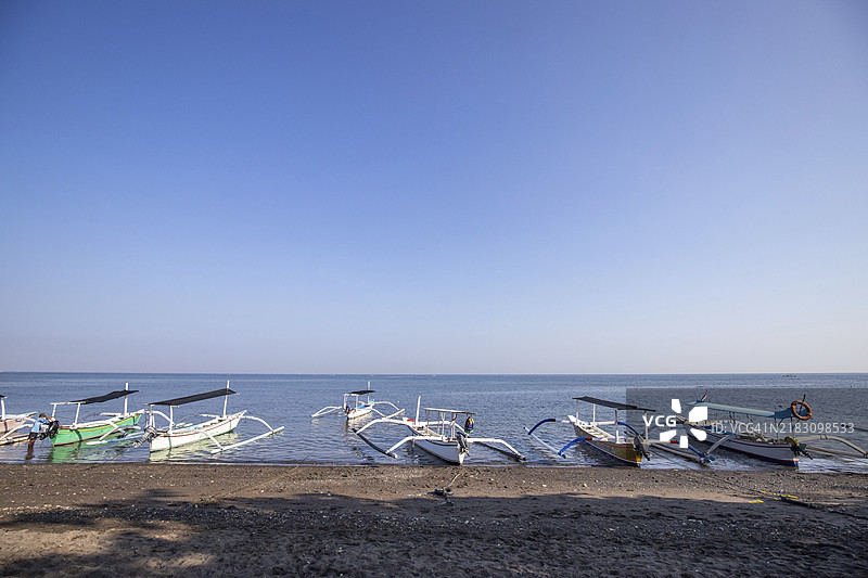 海滩上的朱空船。清晨的阳光下，传统渔船在巴厘岛洛维纳。图片素材