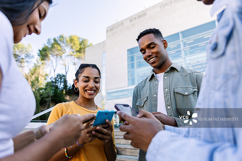 一群年轻的大学生在户外分享手机内容图片素材