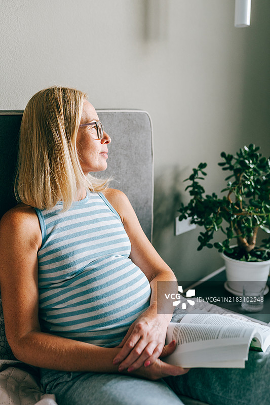 母亲的指导：平静的准妈妈在床上休息，阅读育儿建议，思考未来图片素材