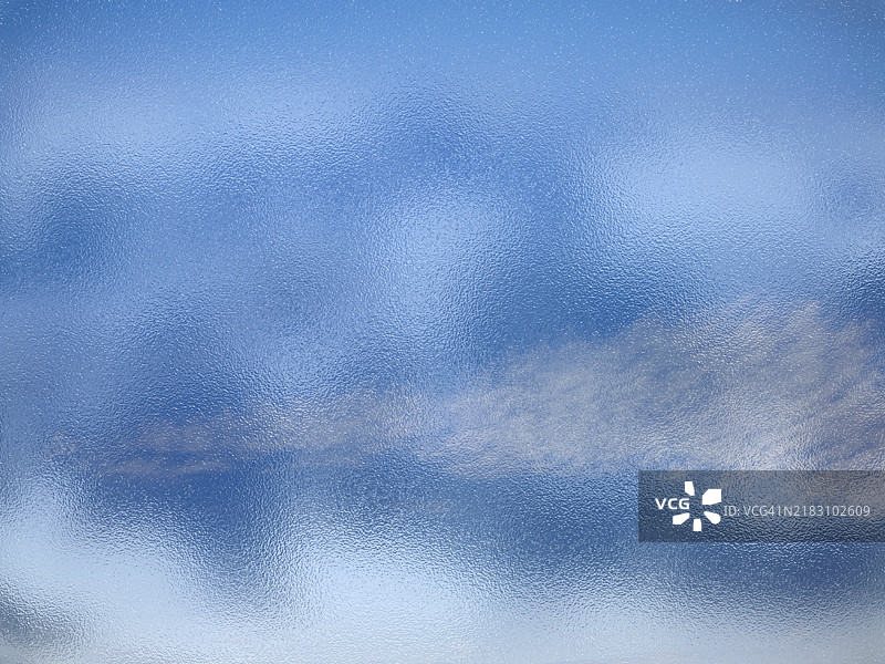 抽象背景，透过透明玻璃看到明亮的蓝天。图片素材