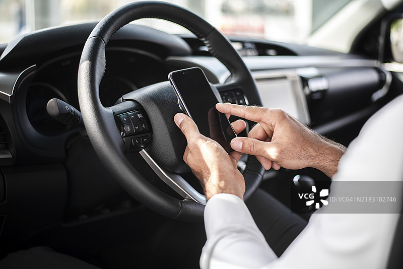 特写镜头：男子握着方向盘查看手机图片素材