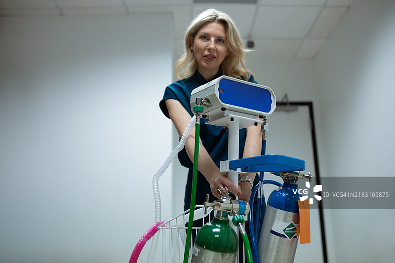 穿着医疗服的女性正在为疼痛缓解设置气体系统，结合氧气和氧化亚氮以提高患者的舒适度。图片素材