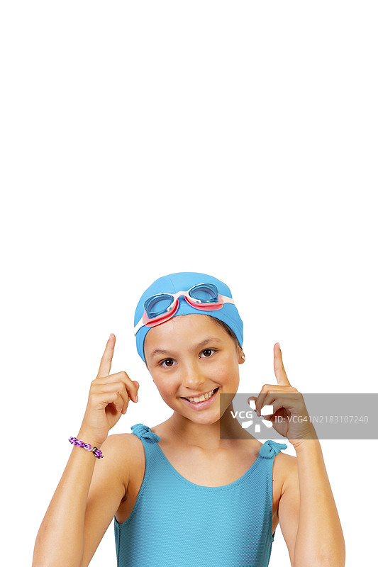 穿泳衣和潜水镜的女孩，在游泳池上游泳课中，指向上方。白色背景留有空白。图片素材