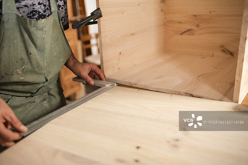 半身视角的男子正在制作一个木制立方体以供摄影使用图片素材