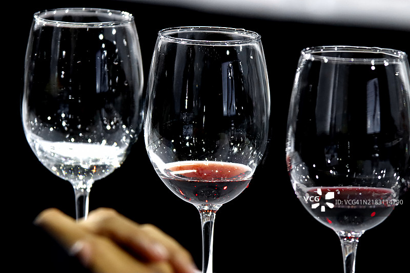 一排酒杯紧挨着排列，杯中盛满了红酒、白酒和玫瑰酒。图片素材