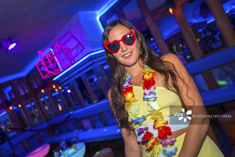 在夜总会派对上，吸引人的拉丁裔女性戴着心形眼镜坐在包厢里。图片素材