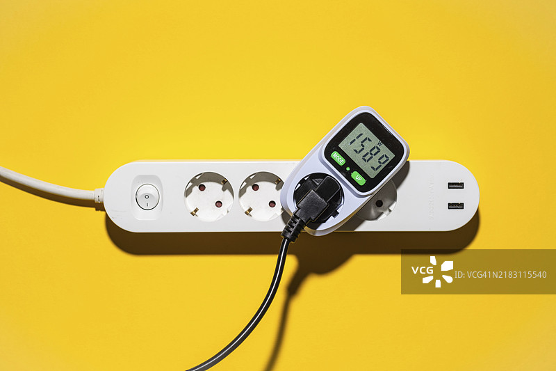 电源插座上的能耗计俯视图，背景为黄色图片素材