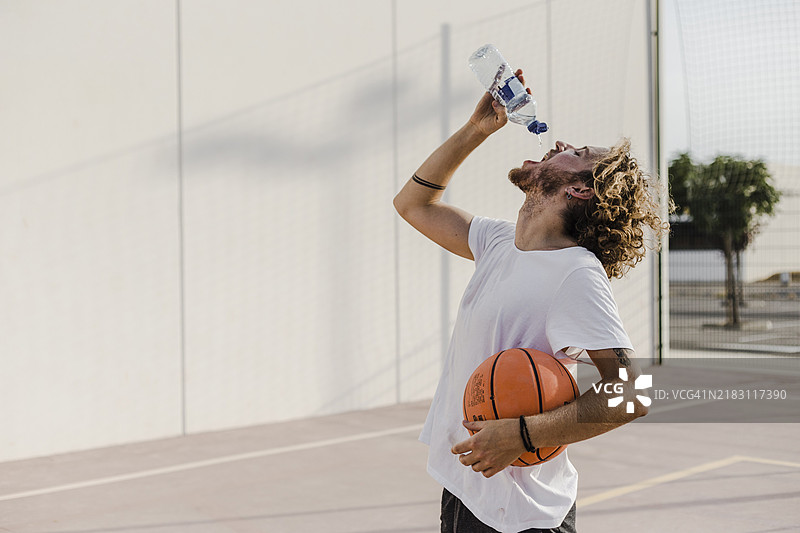 侧面年轻男子拿着篮球喝水图片素材